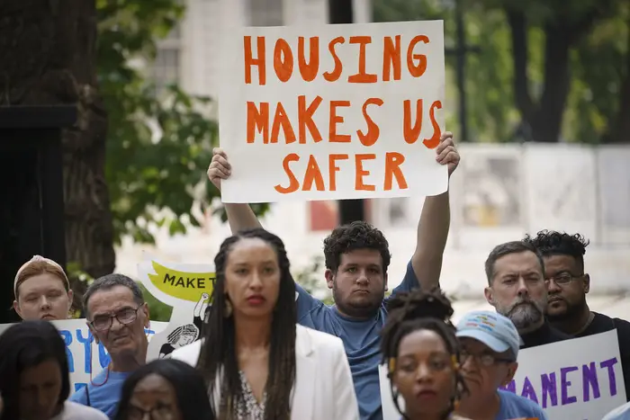 Demonstrators hold signs and wear bright shirts in favor of stronger housing protections.
